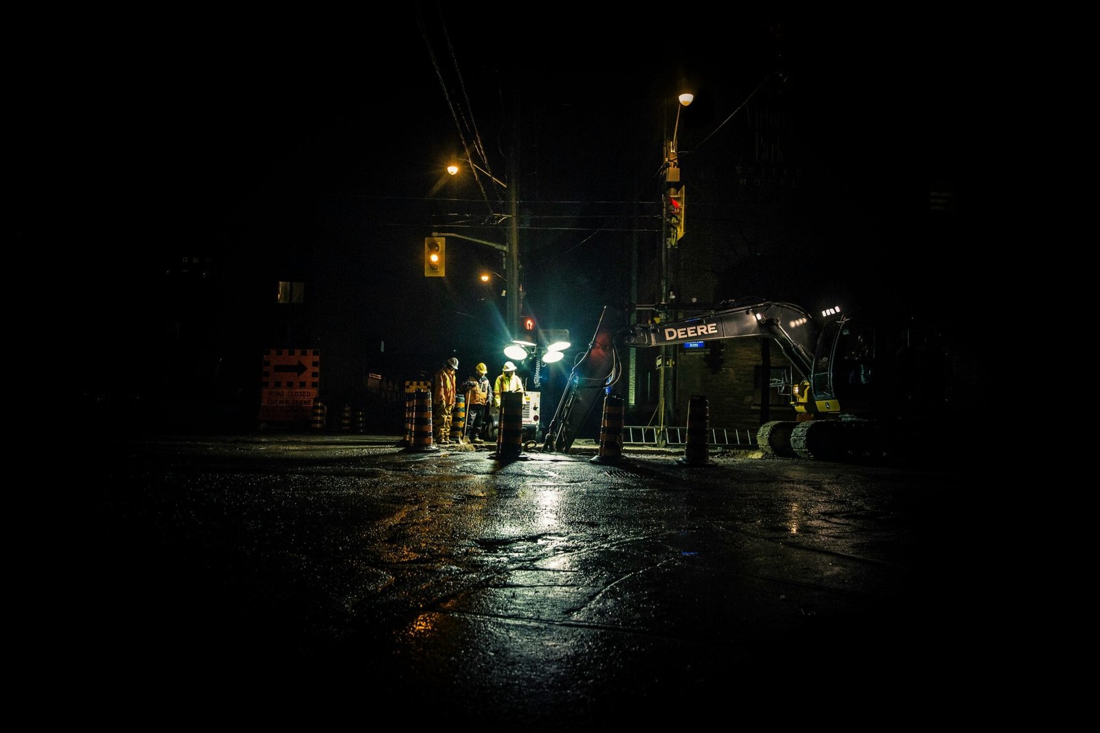 three people standing near utility post with lights turned on during nighttime